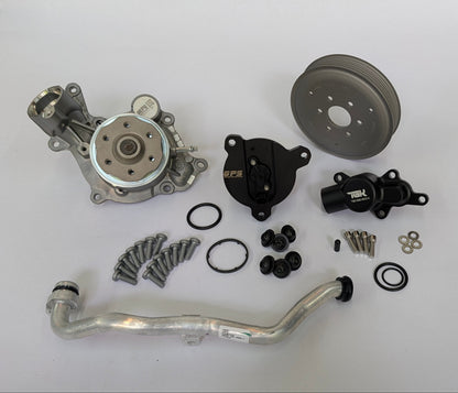An automotive parts kit laid out on a white surface, including a silver metal pump, a black pulley, a black thermostat by German performance solutions, an aluminum radiator hose, gaskets, washers, and screws.